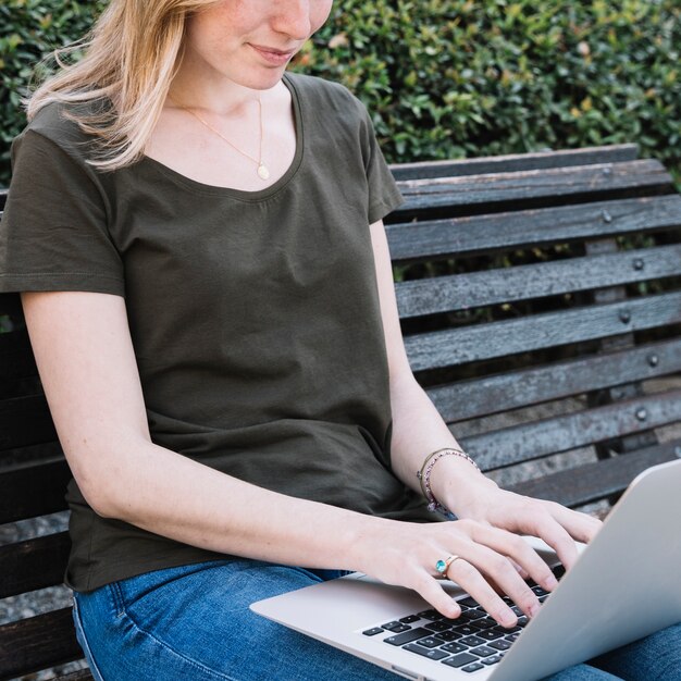 Mujer de la cosecha que usa la computadora portátil en el parque