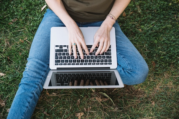 Mujer de la cosecha que usa la computadora portátil en la tierra