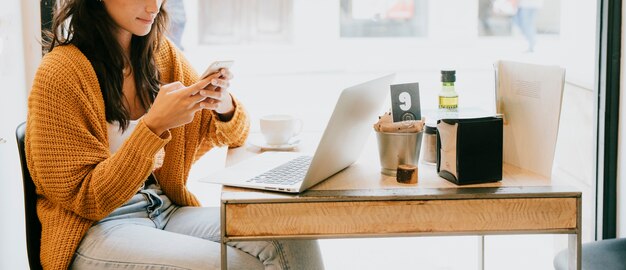 Mujer de la cosecha que usa smartphone en café