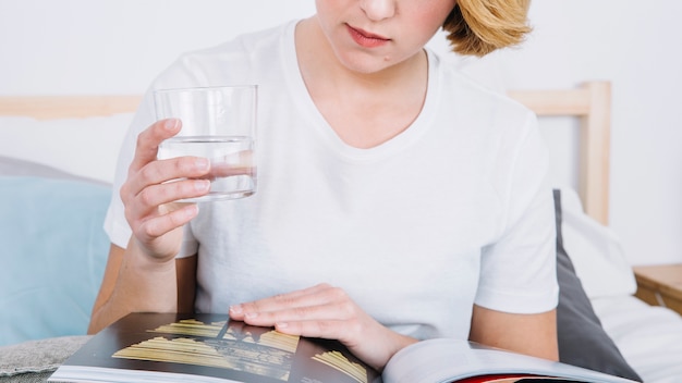 Mujer de la cosecha con la revista de lectura de vidrio