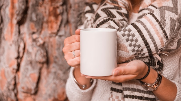 Mujer de la cosecha con la taza cerca del árbol