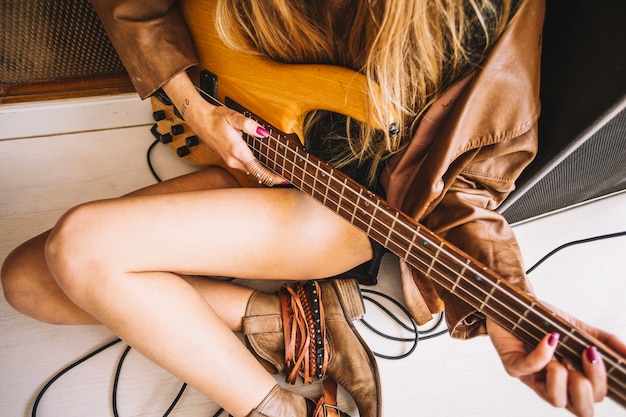 Mujer de la cosecha tocando la guitarra cerca de amplificador