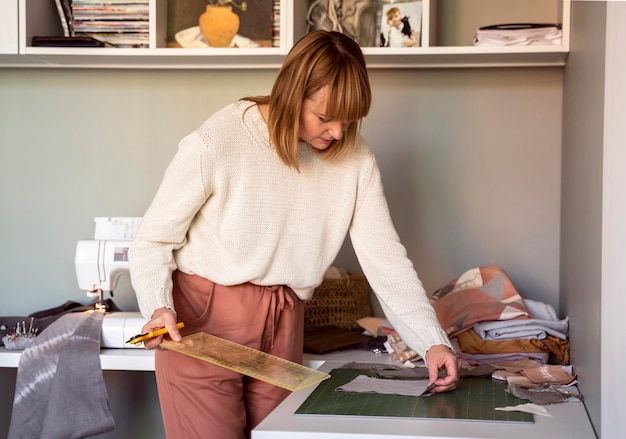 Foto gratuita mujer cosiendo en un lugar de trabajo de sastre