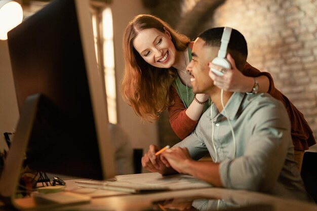 Mujer creativa feliz divirtiéndose con su colega masculino mientras trabaja en la oficina El foco está en la mujer