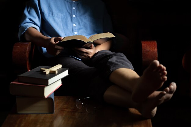 La mujer cristiana se sentó a leer la Biblia en una silla de madera.