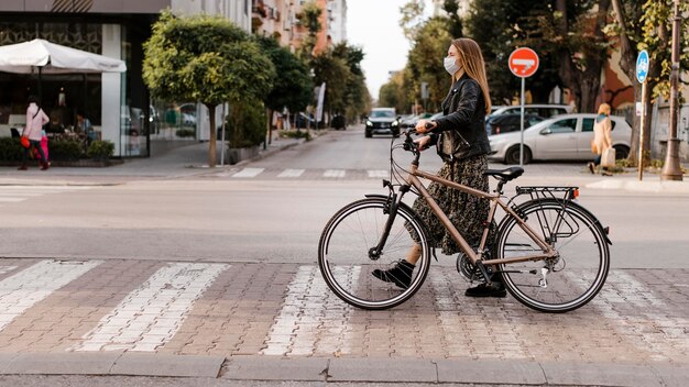 Mujer cruzando la calle junto a su bicicleta