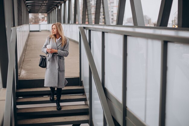 Mujer cruzando el puente y tomando café