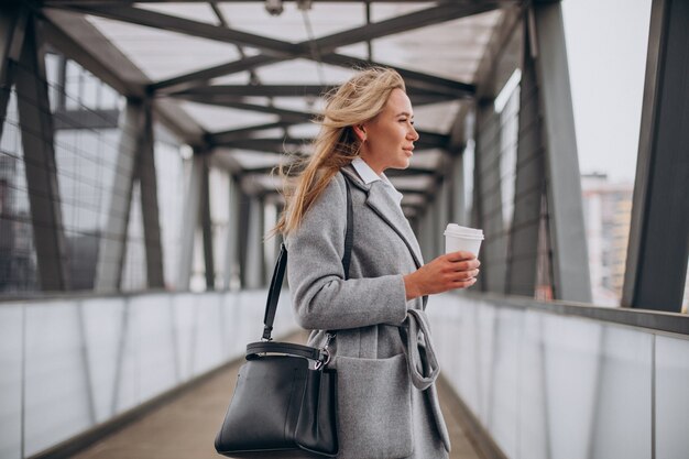 Mujer cruzando el puente y tomando café