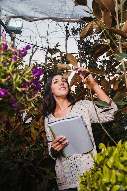 Mujer con cuaderno inspeccionando flores