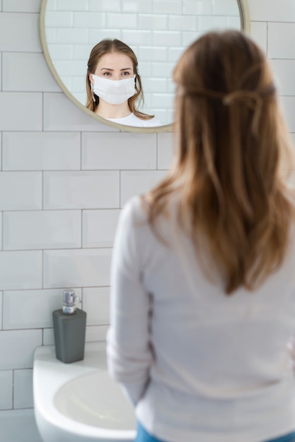 Foto gratuita mujer en cuarentena mirándose en el espejo