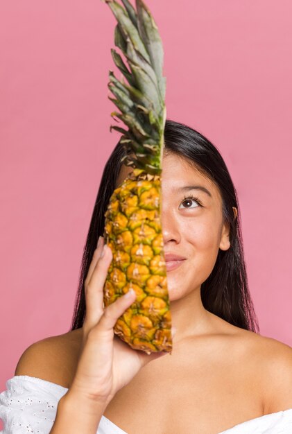 Mujer cubriendo la mitad de su cara con piña