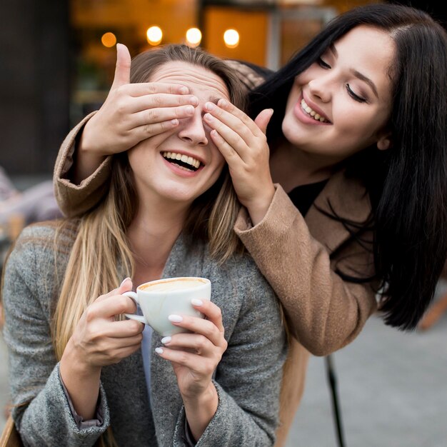 Mujer cubriendo los ojos de su amiga