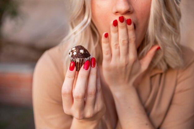 Mujer cubriendo su boca mientras sostiene cupcake