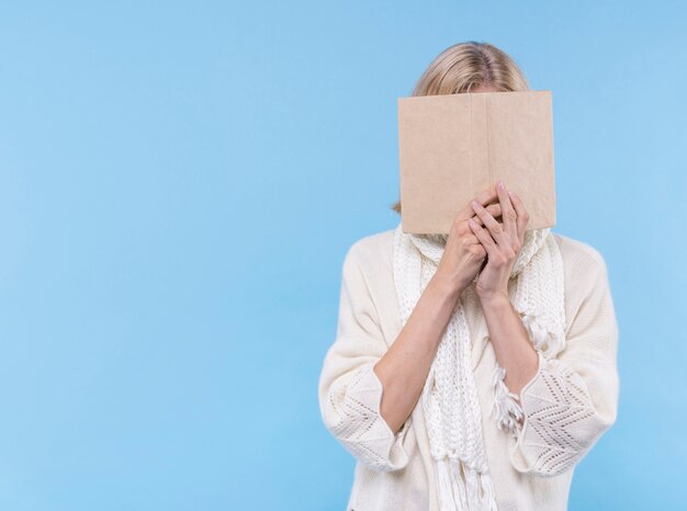 Mujer cubriéndose la cara con un libro