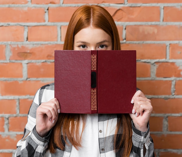 Mujer cubriéndose la cara con el libro