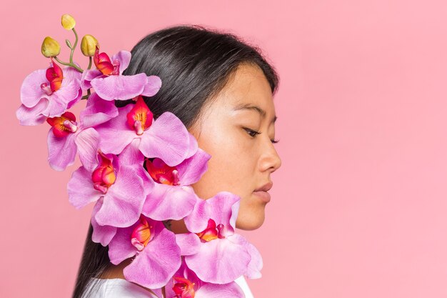 Mujer cubriéndose la cara con pétalos de orquídea de lado