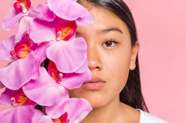 Mujer cubriéndose la cara con pétalos de orquídea