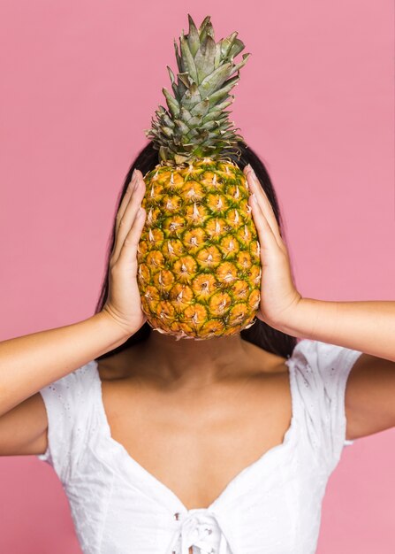 Mujer cubriéndose la cara con piña