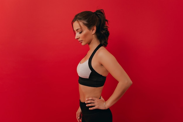 Mujer con cuerpo tonificado haciendo ejercicio en fitness Mujer determinada durante el entrenamiento físico en pared aislada