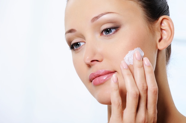 Foto gratuita mujer cuidando su rostro con crema humectante