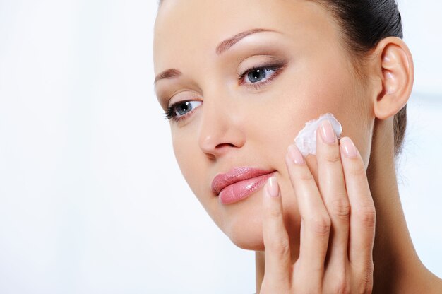 mujer cuidando su rostro con crema humectante