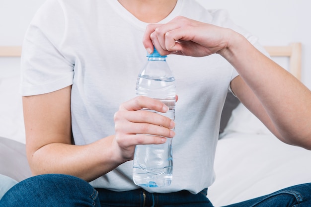 Mujer de cultivo abriendo la botella de agua