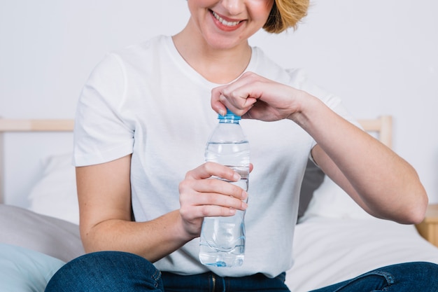 Mujer de cultivo abriendo botella de agua
