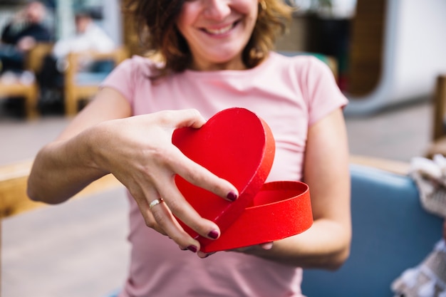 Foto gratuita mujer de cultivo abriendo caja en forma de corazón