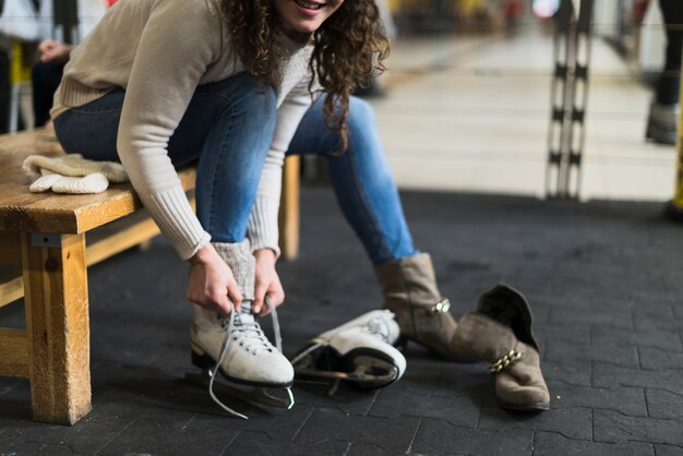 Mujer de cultivo atar patines de hielo