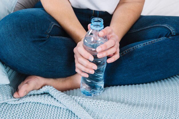 Mujer de cultivo con botella en la cama