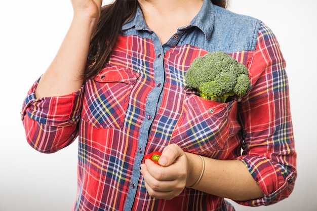 Mujer de cultivo con brócoli en el bolsillo