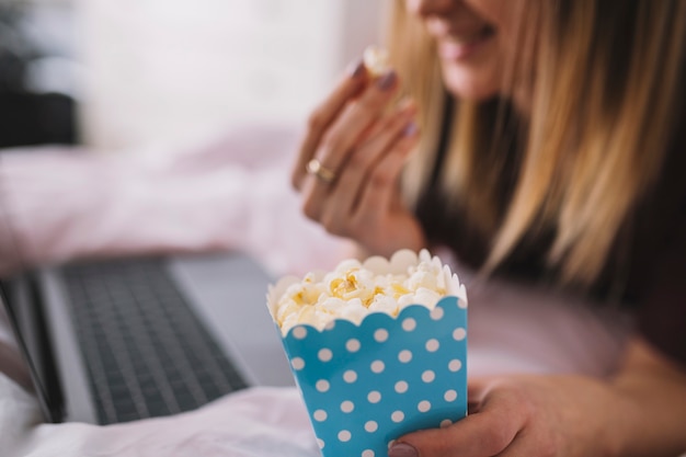 Foto gratuita mujer de cultivo comiendo palomitas de maíz mientras mira la película