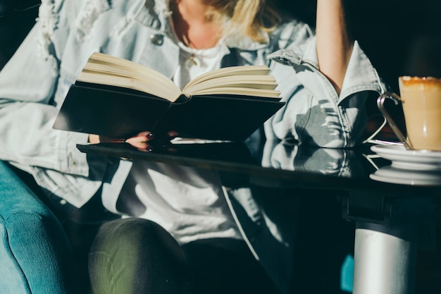 Mujer de cultivo leyendo en café