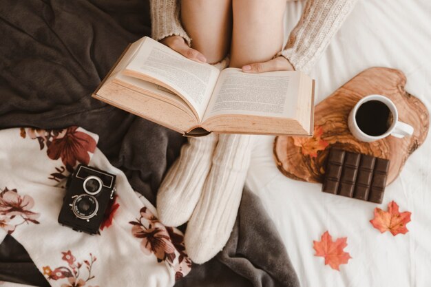 Mujer de cultivo leyendo cerca de cámara y merienda