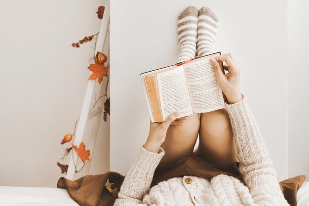 Mujer de cultivo leyendo cerca de la pared