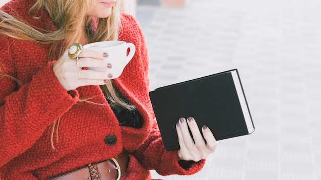 Mujer de cultivo con libro y taza