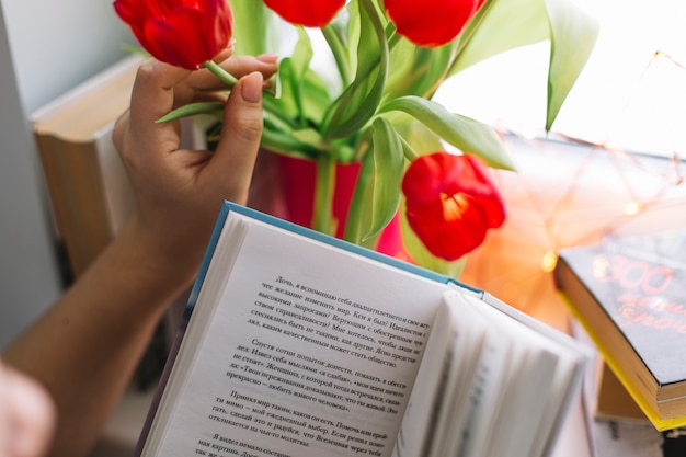 Mujer de cultivo con libro tocando flores