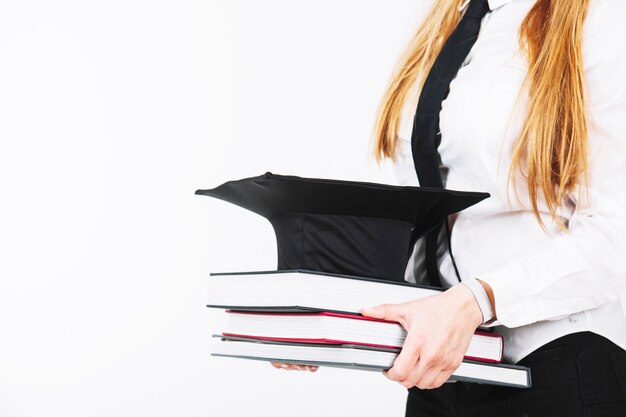 Mujer de cultivo con libros y gorra académica