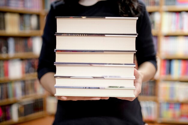 Mujer de cultivo con pila de libros