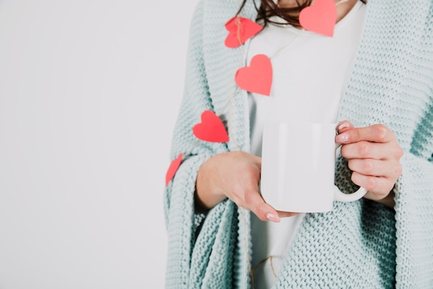 Mujer de cultivo en plaid sosteniendo la taza