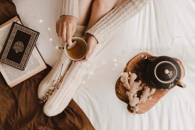 Mujer de cultivo prepara té cerca de libros y jengibre