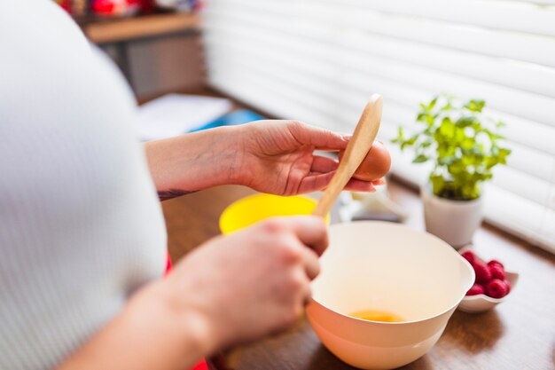 Mujer de cultivo rompiendo huevos para pastelería