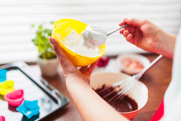 Mujer de cultivo tomando crema batida para pastelería