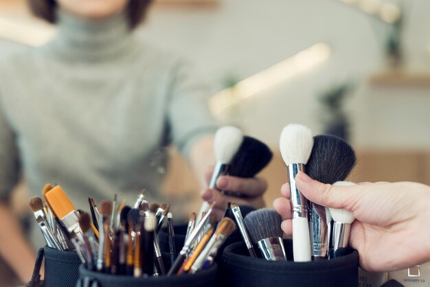 Mujer de cultivo tomando pinceles de maquillaje