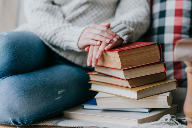 Mujer de cultivos cerca de la pila de libros