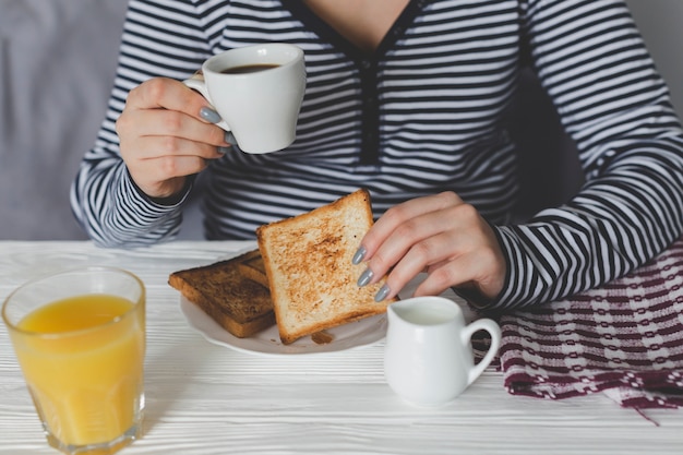 Mujer de cultivos disfrutando de tostadas y café