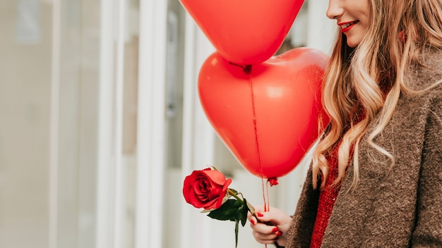 Foto gratuita mujer de cultivos con globos y rosa