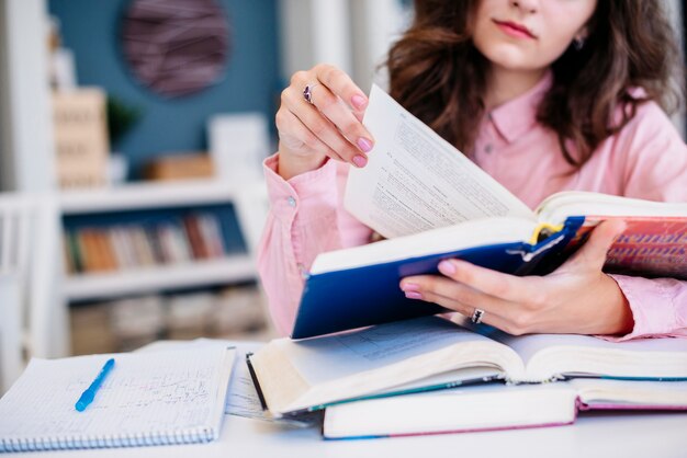 Mujer de cultivos leyendo libros de texto en la biblioteca