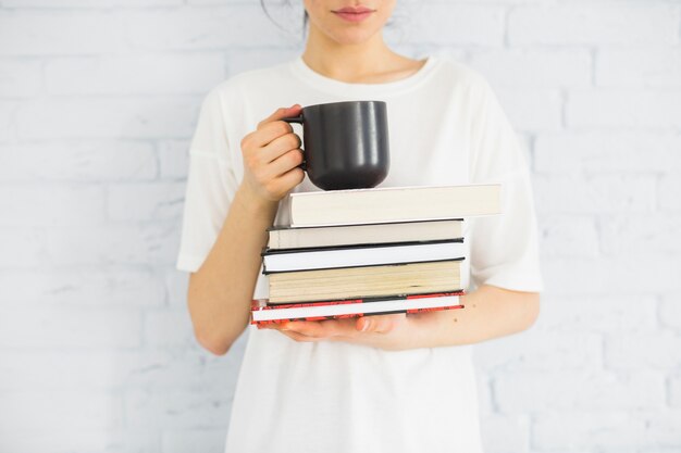 Mujer de cultivos con libros y taza