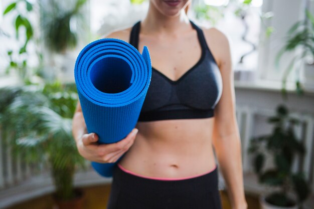 Mujer de cultivos con tapete de yoga